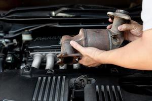 Close up old catalytic converter in hand Technician remove from engine gasoline car dust clogged condition on filter in service concept photo