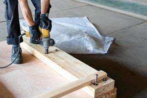 Worker use Drill machine Fasten nut of wooden box packing  work in factory photo