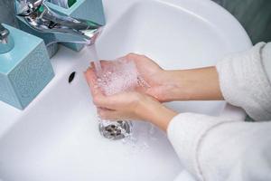 mujer se lava la mano en el lavabo del baño, sin rostro foto