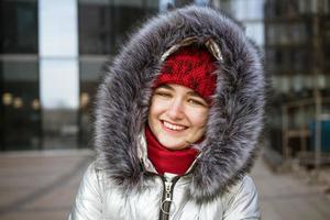 young happy woman in a warm jacket with a backpack travels the cities photo