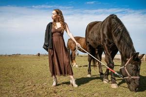 hermosa joven en un campo con caballos. atractivo modelo de moda. foto