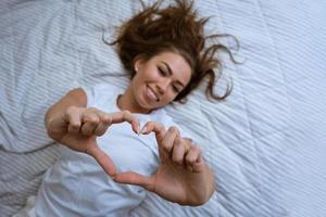 una joven feliz se despierta en una cómoda cama blanca foto