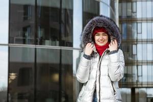 young happy woman in a warm jacket with a backpack travels the cities photo