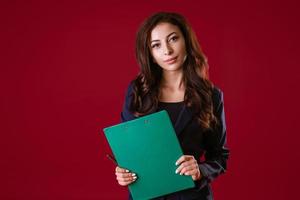 A woman director is holding documents and smiling on a red background. photo