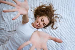 Overjoyed woman in pajamas stretching out her arms photo