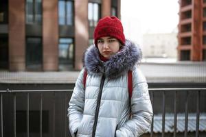 young happy woman in a warm jacket with a backpack travels the cities photo