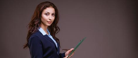 Stylish business woman with a folder in her hands. On dark background photo