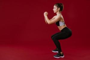 young woman is engaged in fitness on a red background photo