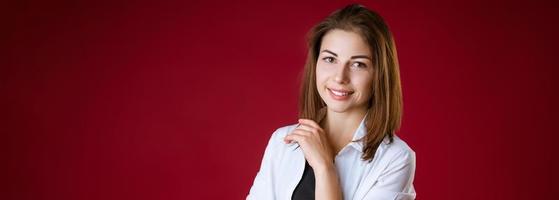 A woman is standing and smiling against a red studio background photo