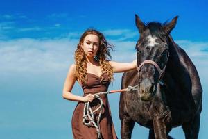 beautiful woman standing in a field with a horse photo