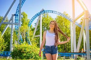 Happy smile girl stands in an amusement Park on a Sunny day. Trendy portrait . photo