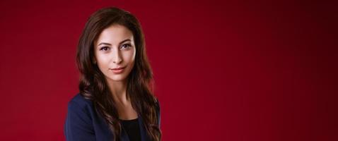 Beautiful young business woman in a suit on a red background photo
