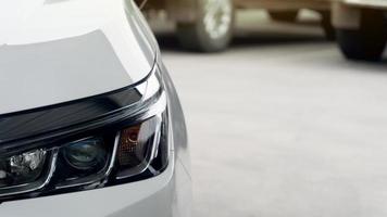 Headlights of a white car in the parking lot. Blurred view of other cars in the distance behind. photo