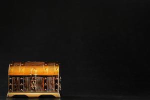 A chest made of gold with jewels on a black background. photo