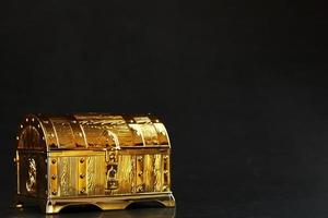 A chest made of gold with jewels on a black background. photo