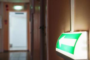 Evacuation arrow with illumination from the building to the room, guiding to the exit. photo