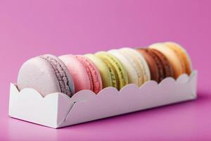 Colorful French macarons cookies in a package on a pink background. photo