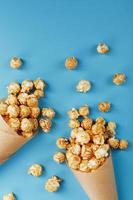 Caramel popcorn in a paper envelope on a blue background. photo