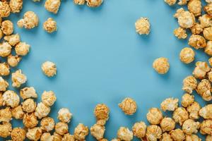 Caramel popcorn by a ripple on a blue background, in the form of a frame. photo