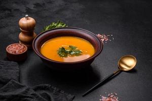 Delicious hot pumpkin and carrot soup puree with spices and herbs photo