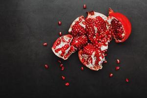 The opened Fruits of a ripe open pomegranate lie on a black textural background. photo