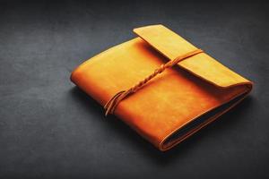 The leather cover of the album is made of brown handmade genuine leather on a black background. Elements of a leather product close-up. photo