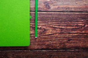 Green Notepad with a felt-tip pen on a brown wooden table, top view. photo