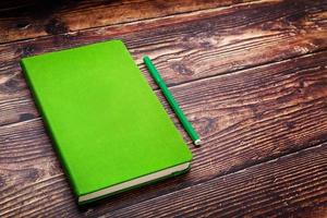 Green Notepad with a felt-tip pen on a brown wooden table, top view. photo