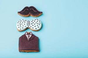 Glazed gingerbread in the form of a mustache, butterfly and tuxedo, men's set on a blue background. Handmade cookies. photo