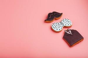 Glazed gingerbread in the form of a mustache, butterfly and tuxedo, stars men's set on a pink background. Handmade cookies. photo