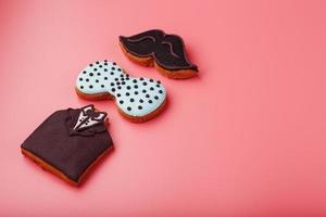 Glazed gingerbread in the form of a mustache, butterfly and tuxedo, stars men's set on a pink background. Handmade cookies. photo