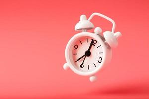 White retro style alarm clock in levitation isolated on pink background. photo