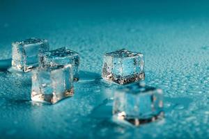 Ice cubes are scattered with water drops scattered on a blue background. photo