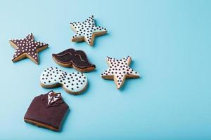 Glazed gingerbread in the form of a mustache, butterfly and tuxedo, stars men's set on a blue background. Handmade cookies. photo