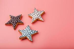 A close-up of three homemade glazed gingerbread cookies is made in the form of stars on a pink background. Handmade cookies. photo