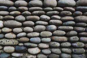 The texture of the stone wall, masonry of natural oval stones. photo