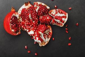 The opened Fruits of a ripe open pomegranate lie on a black textural background. photo