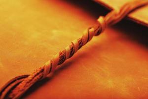 The leather cover of the album is made of brown handmade genuine leather on a black background. Elements of a leather product close-up. photo