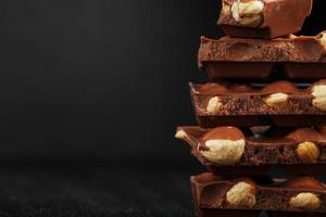 Chocolate with hazelnut in the form of a tower on a dark background. Pieces of milk chocolate with nuts. photo