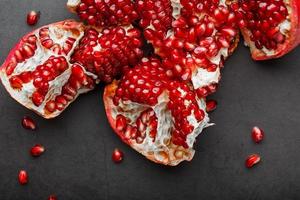 The opened Fruits of a ripe open pomegranate lie on a black textural background. photo