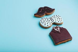 Glazed gingerbread in the form of a mustache, butterfly and tuxedo, men's set on a blue background. Handmade cookies. photo