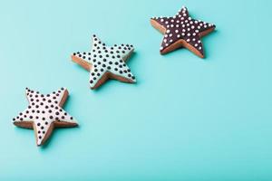 Close-up of three homemade glazed gingerbread cookies made in the form of stars on a blue background. Handmade cookies. Free space. photo