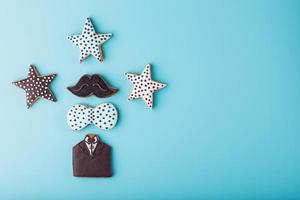 Glazed gingerbread in the form of a mustache, butterfly and tuxedo, stars men's set on a blue background. Handmade cookies. photo