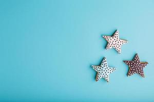 Close-up of three homemade glazed gingerbread cookies made in the form of stars on a blue background. Handmade cookies. Free space. photo