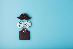 Glazed gingerbread in the form of a mustache, butterfly and tuxedo, men's set on a blue background. Handmade cookies. photo