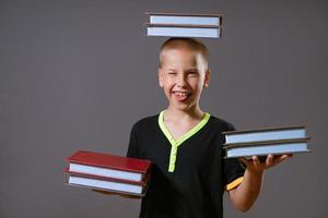 little boy hold the stacks of books in your hands and on your head photo
