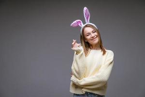 smiling young girl with bunny ears  shows a mini heart with fingers photo