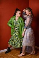 Two beautiful women with bright makeup and bright clothes are posing in studio. photo