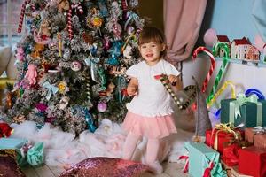 a little girl plays near the Christmas tree photo