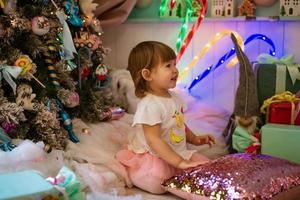 a little girl plays near the Christmas tree photo